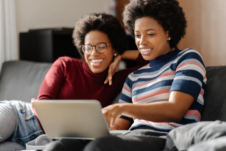 Two Black twin sisters spending time using laptop together at home
