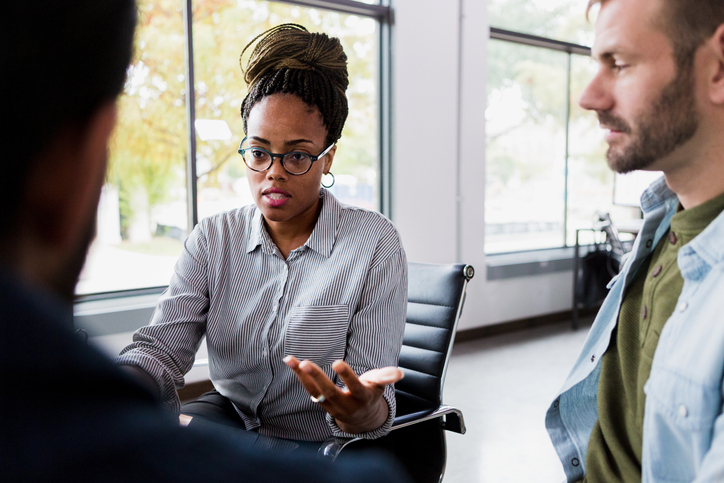 Female mid adult manager expresses frustration to male employees
