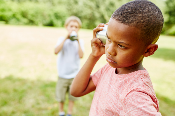 Close-Up Of Cute Kids Communicating Through Tin Can Phone At Park