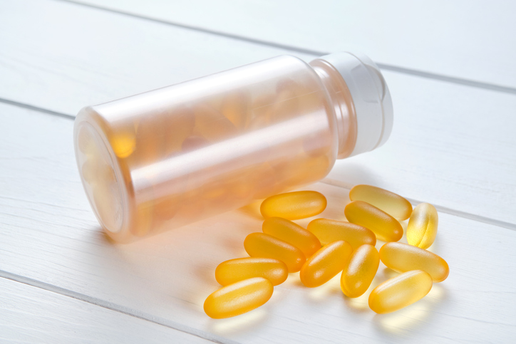 Omega-3 fish oil capsules, on a wooden spoon, isolated on a white background or table. Healthy lifestyle, prevention and treatment of diseases. Taking food supplements and vitamins. Biologically active additive.