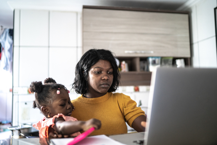 Mother doing homeoffice while holding her baby girl