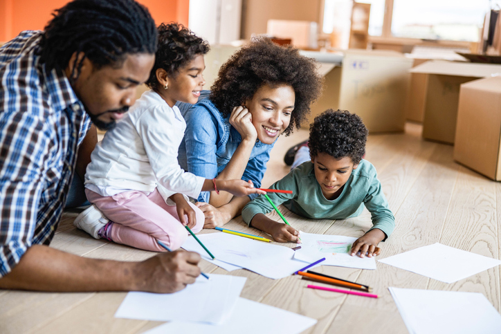 Happy black family coloring on the floor at their new home.
