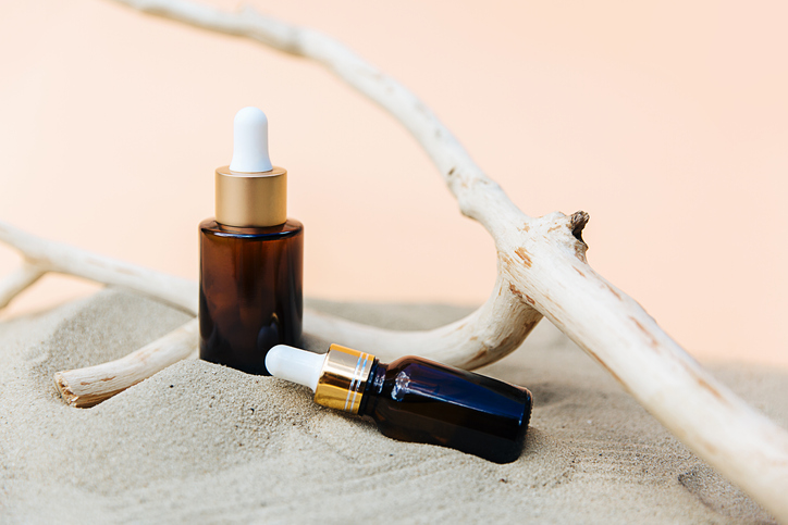 Spa cosmetics in brown glass bottles on broun background. Copy space for text. Beauty blogger, salon therapy, branding mockup, minimalism concept. Various Facial Massage Oils For Spa Treatment.