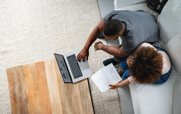African American couple paying bills online at home