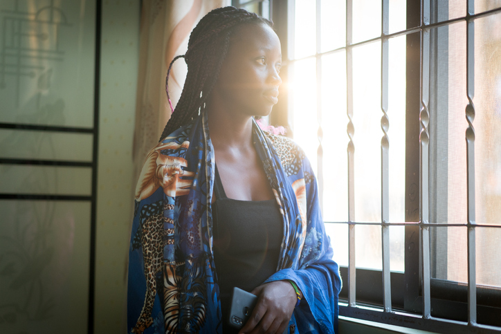 Women looking through window contemplating and thinking at home