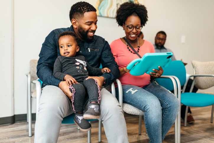 Black family filling out paperwork in doctors office lobby