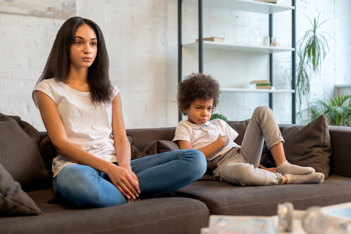 Young mother and her little kid sitting together in room at home