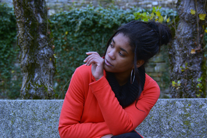 Young Woman Looking Away While Sitting Against Tree