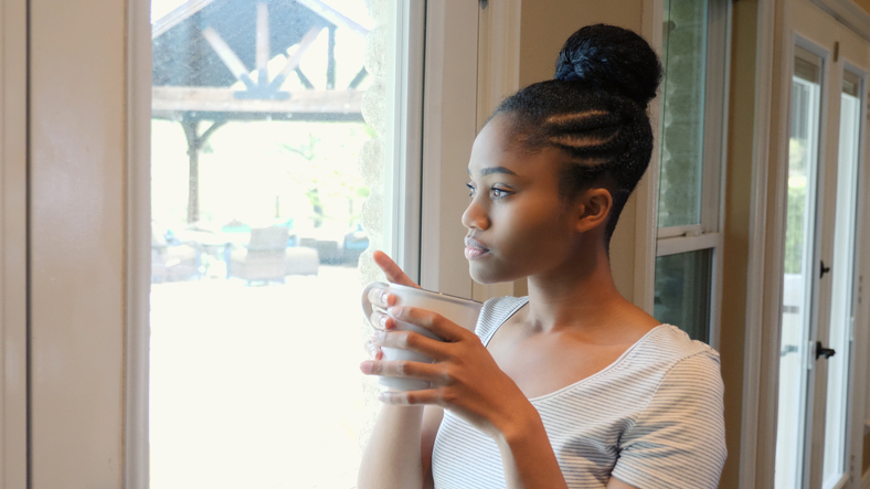 Introspective young woman daydreams at home
