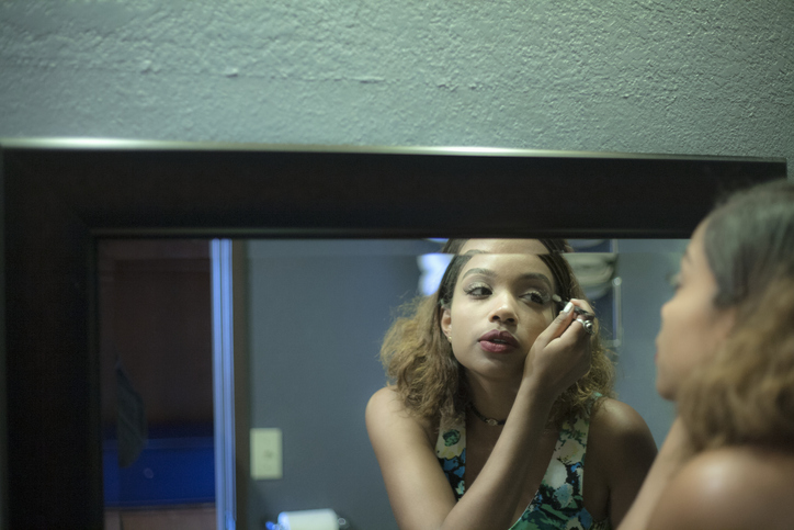 Young woman applying eyeliner while looking at mirror reflection
