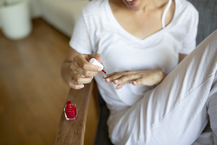 Focus on a young African American woman at home, giving herself a beauty treatment
