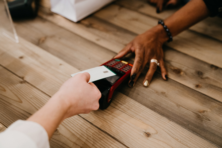 Young woman is paying using her credit card with contactless technology in a shop