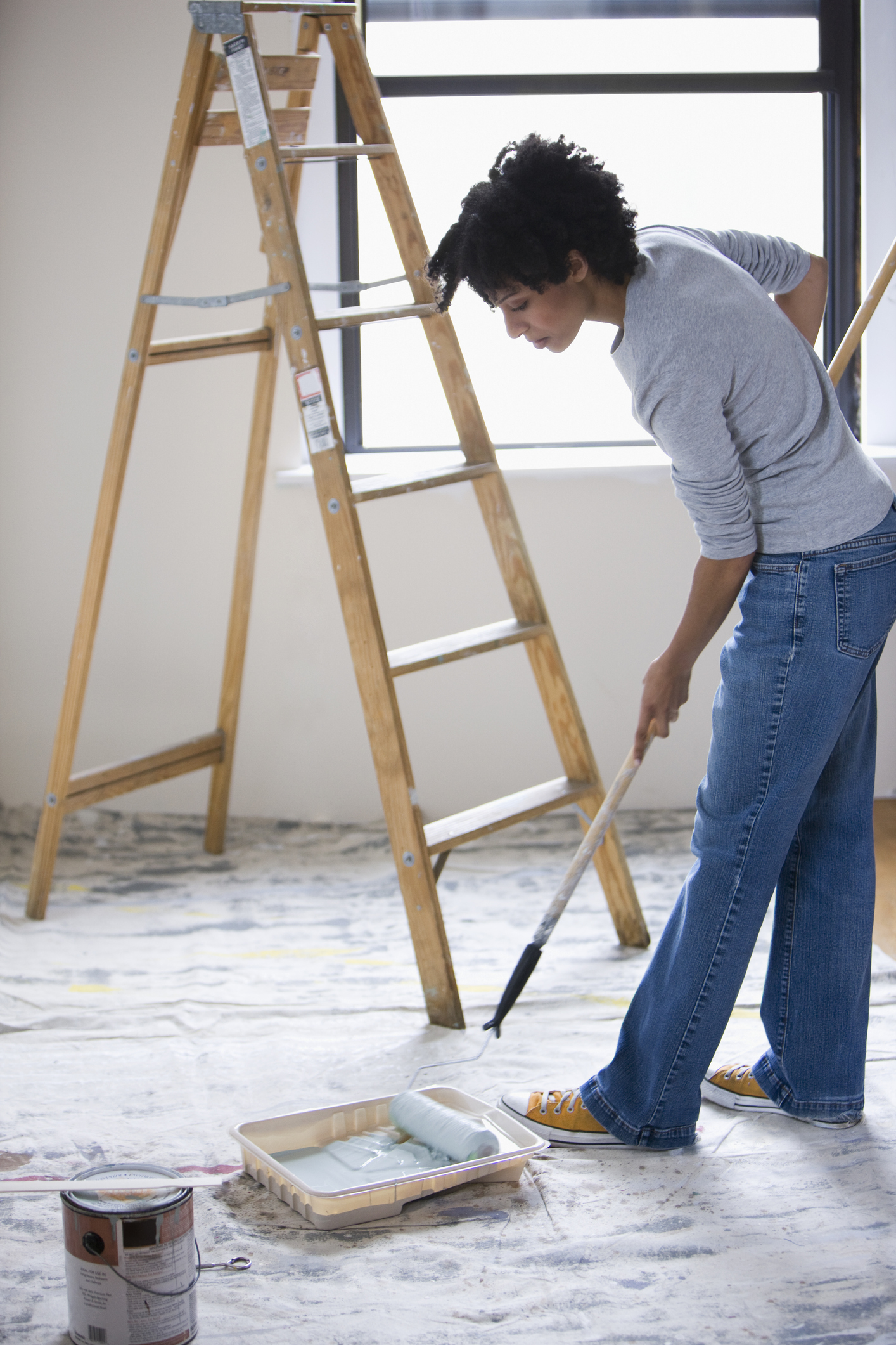 Mixed race woman painting with paint roller