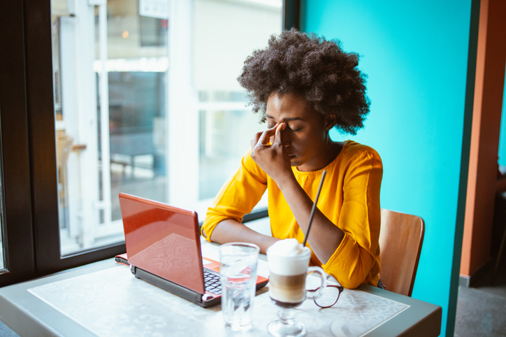 Tired and worried young African-American woman working on a laptop