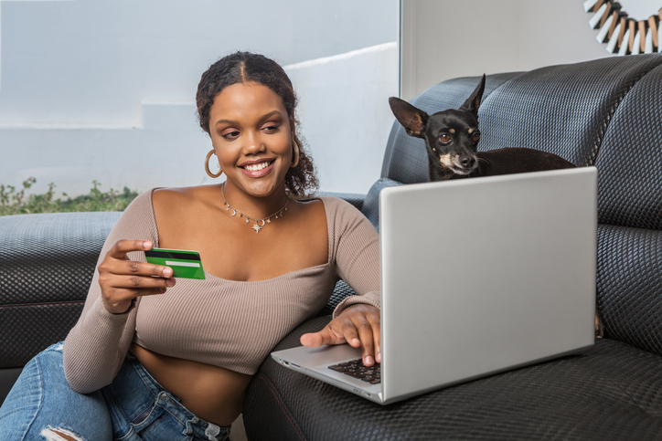 African American woman making online purchases near dog