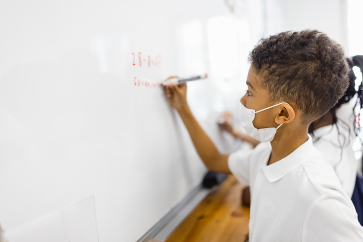 Primary school boy and girl writing on the white board in Classroom