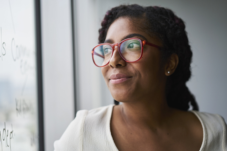 Portrait of cheerful businesswoman looking out window in conference room