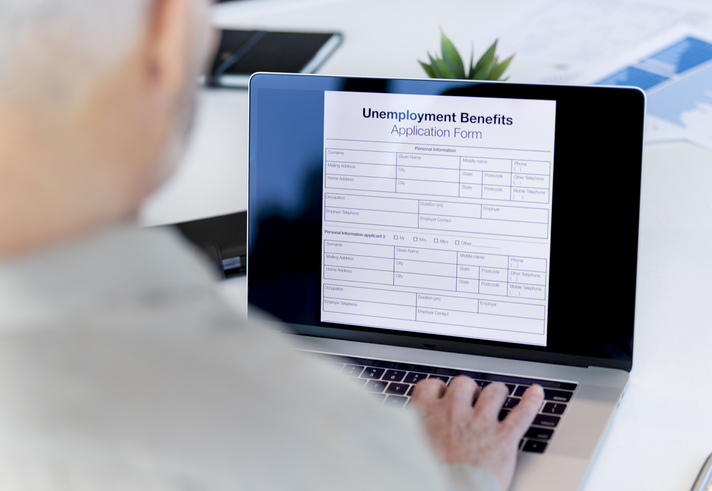 Mature man filling out an online unemployment benefits application form.