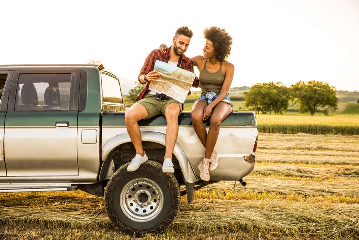 Young couple sitting in the car reading a road map