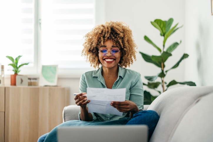 Portrait of a Beautiful Woman Looking at a Document While Working on her Laptop