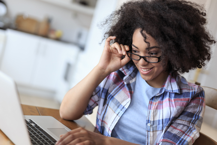African woman sitting at home and working online on her laptop