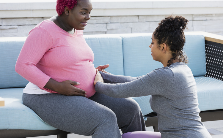 Pregnant woman with doula touching baby bump