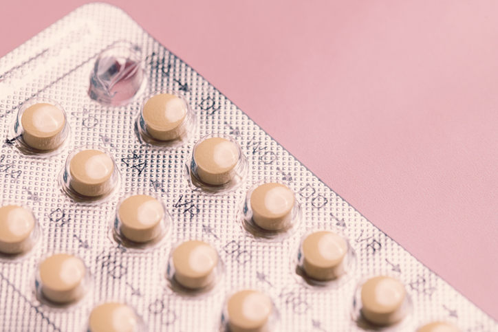 Contraceptive birth control pills on a pink background
