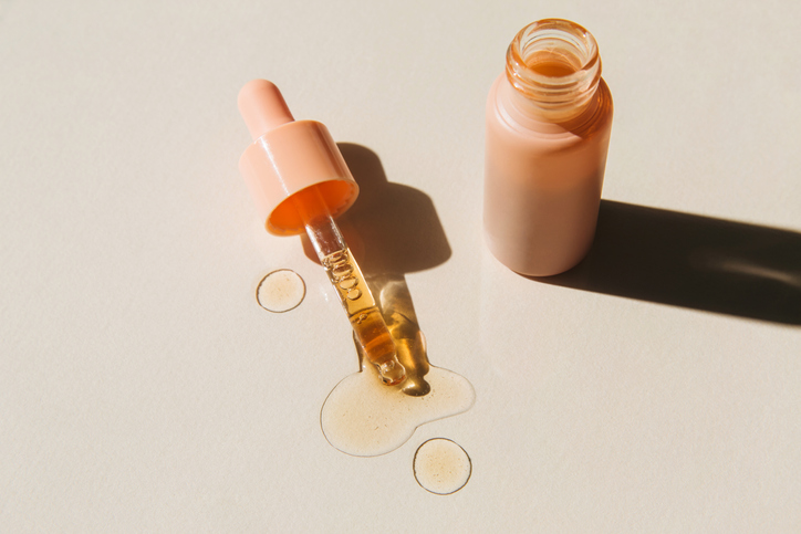 Pipette with cosmetic liquids next to glass bottle on beige background. Beauty product with peptides, ceramides, hyaluronic gel, polyglutamic acid, essential oil, CBD, retinol, collagen. Multitasking beauty. Flat lay, top view, copy space