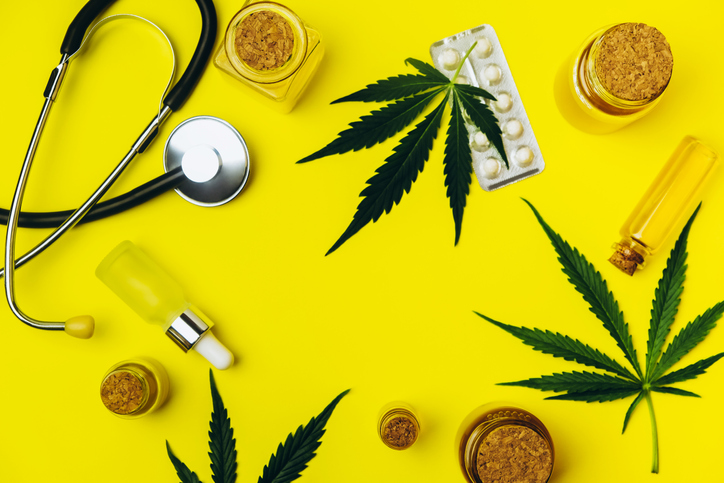 Stethoscope, green cannabis, white pills, jars with thc oil.
