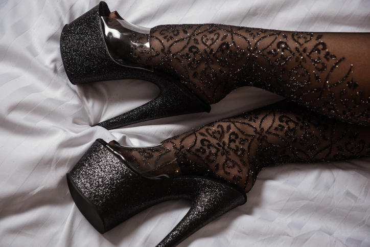 Low Section Of Woman Wearing High Heels On Bed