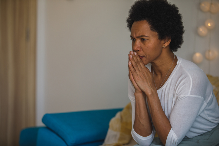 Woman sitting with praying hands in front of face, contemplating