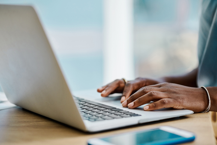 Hands of an african businesswoman browsing on a laptop in an office alone