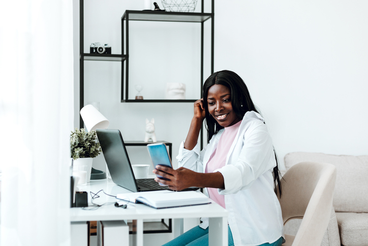 Beautiful young Black woman making selfie while studying at home.