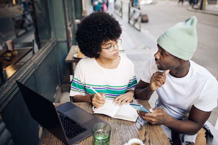 African American young couple on vacation enjoying at the cafe and writing impressions
