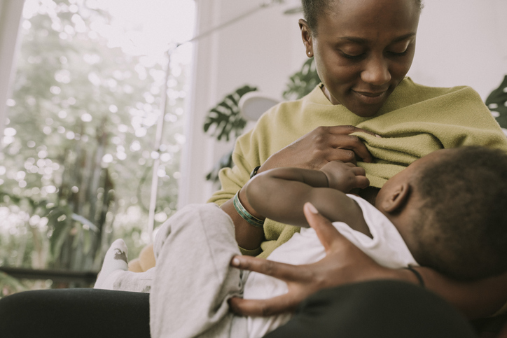 Mother breastfeeding her baby boy at home