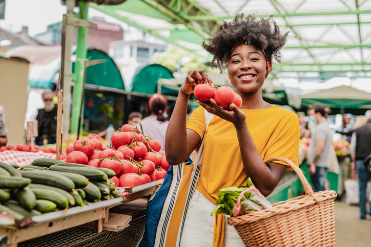 Portrit of a young African woman holding tomatoes at the farmers market