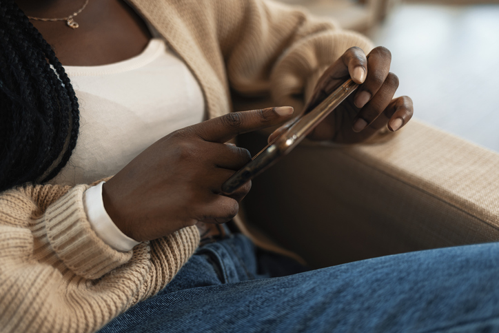 African young woman is typing on touch screen mobile phone
