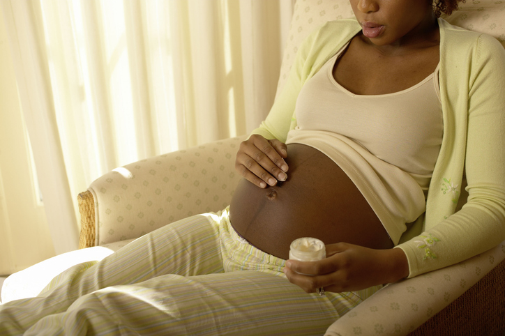 Pregnant woman rubbing stretch mark cream