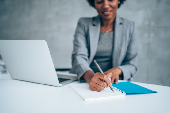 Confident businesswoman working on laptop and taking notes.