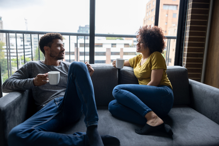 Couple relaxing at home drinking a cup of coffee on the couch