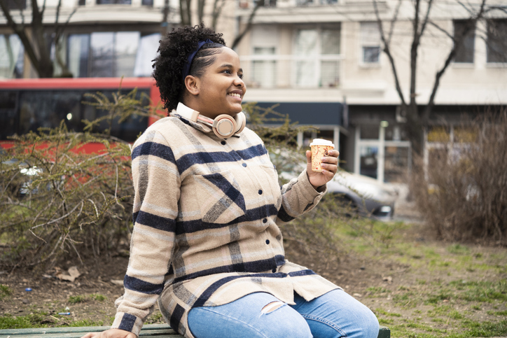 Beautiful Afro girl enjoying coffee and music in the city