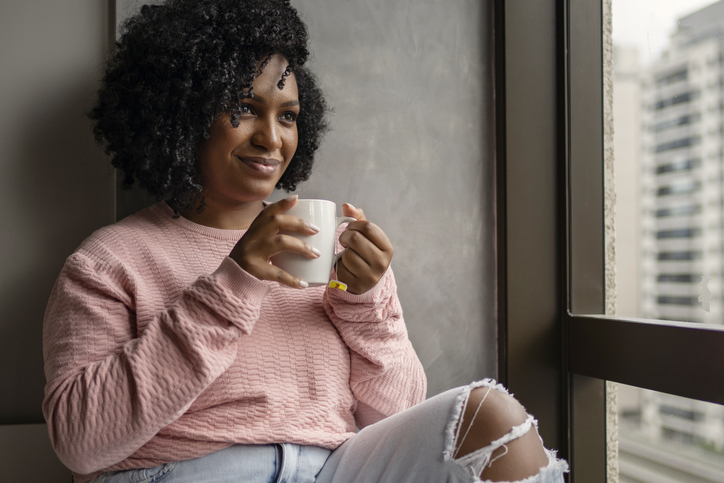 African American woman drinking tea near the window at home