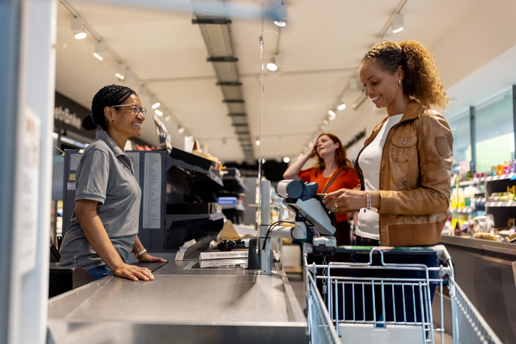 Smiling woman making contactless payment for the purchase in supermarket
