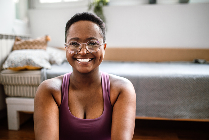 Portrait of young, smiling, pretty woman, doing yoga at home.