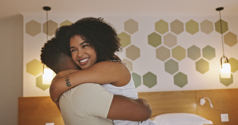 Couple hugging in the bedroom. Husband and wife embracing before bed. Girlfriend giving her boyfriend a hug. Man and woman bonding. Woman holding her male partner. Man holding his girlfriend