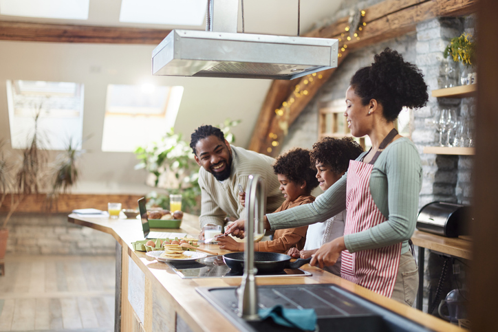 Happy black family preparing pancakes in the kitchen.