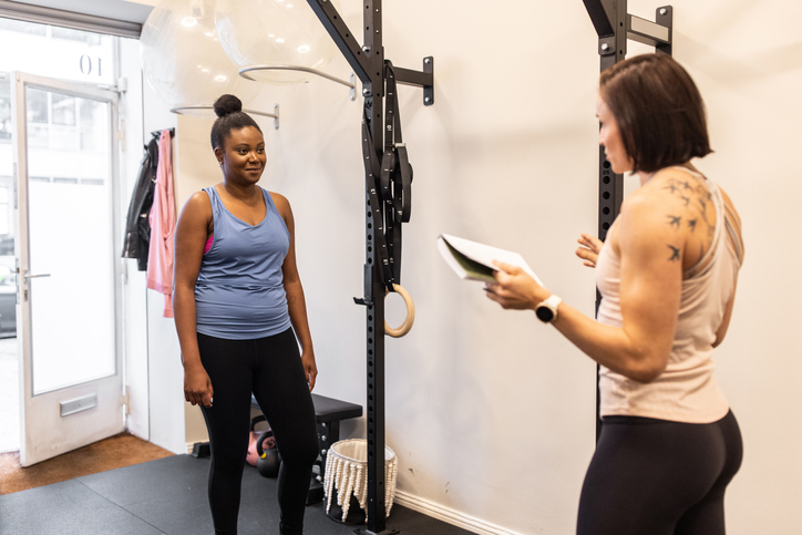 Fitness trainer talking with a woman student in the fitness center