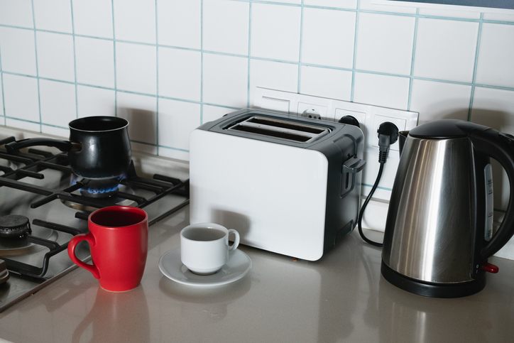 Coffee is brewed in a Turk on a gas stove, on fire. Making coffee for breakfast. A Turk for making Turkish coffee, in the kitchen at home or in a hostel. There is a bright mug next to it. Do it yourself. Home life.