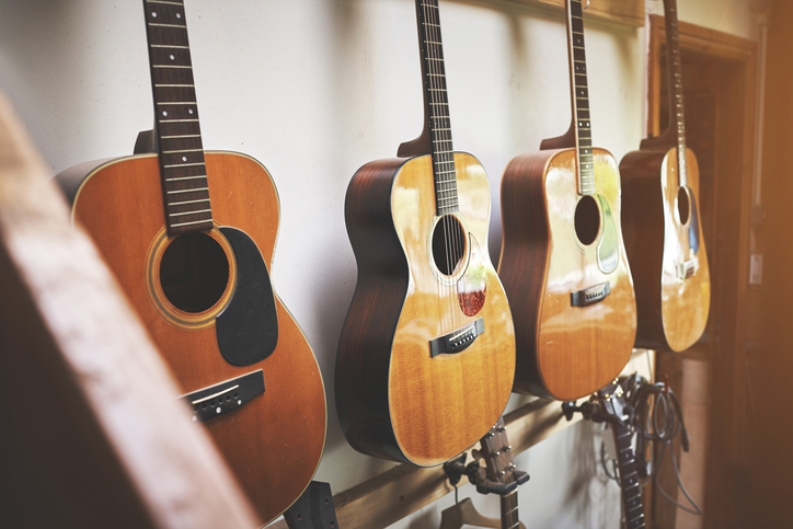 Group of classic musical guitar instruments on display in a music shop. Classical vintage acoustic guitars or instruments made from art wood hanging on a rack in a new indoor local store.