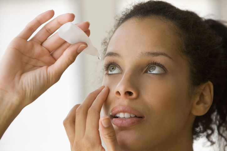 Young woman putting eye drops
